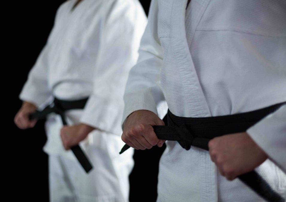 Mid section of Two karate fighters performing karate stance against black background Mid section of Two karate fighters performing karate stance against black background